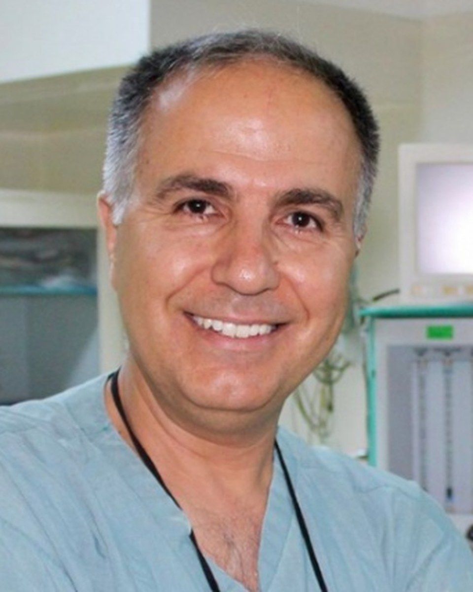 Op. Dr. Hüsrev Çetin smiling in surgical scrubs in the operating room